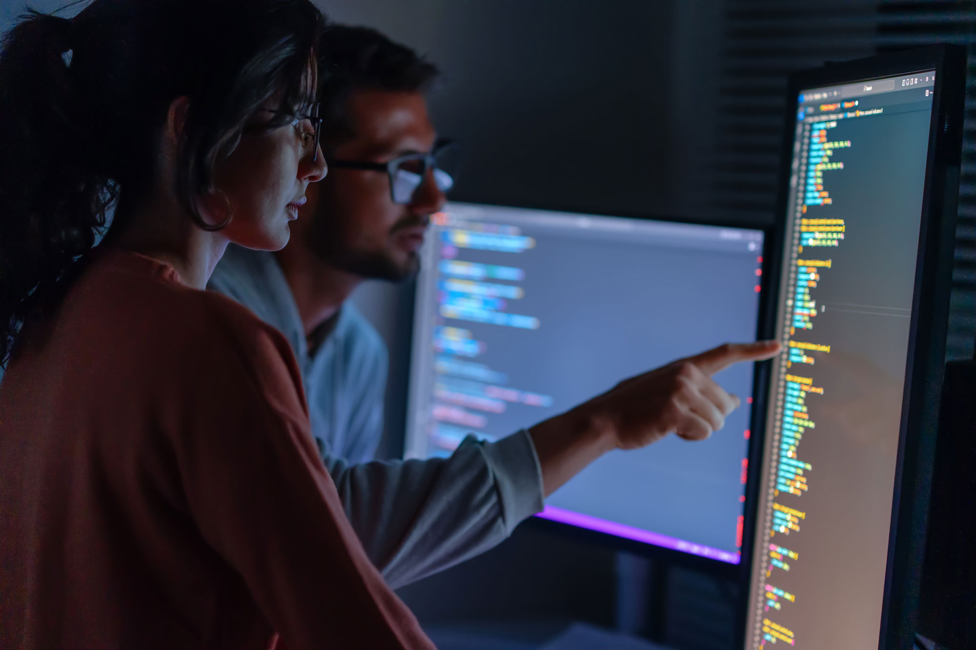 Två kollegor hjälps åt att lösa ett problem i programmeringskod